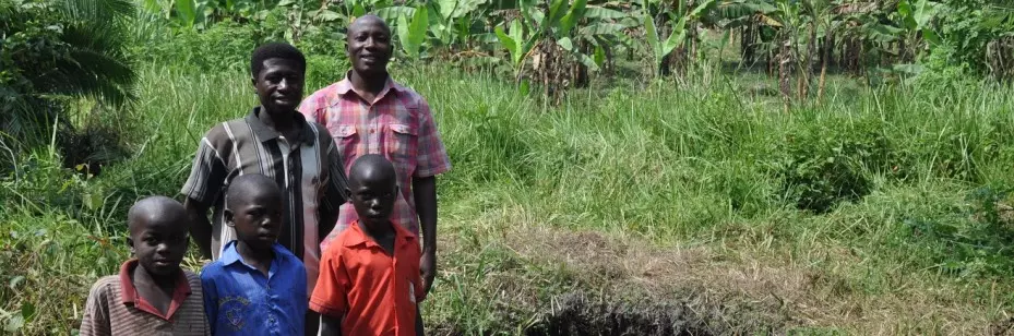Ugandan family standing in front of spring where they collect water that Veolia has helped decontaminate.