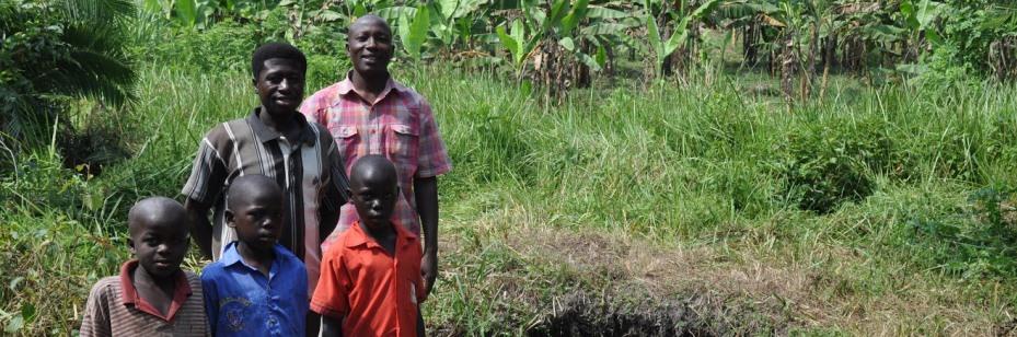 Ugandan family standing in front of spring where they collect water that Veolia has helped decontaminate.