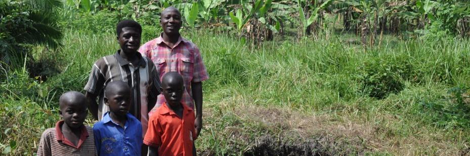 Ugandan family standing in front of spring where they collect water that Veolia has helped decontaminate.