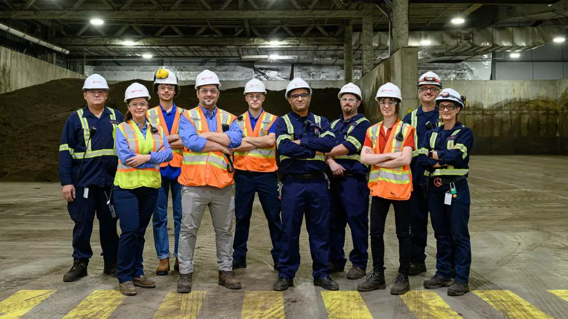 A group of Veolia employees stands in a facility smiling at the camera