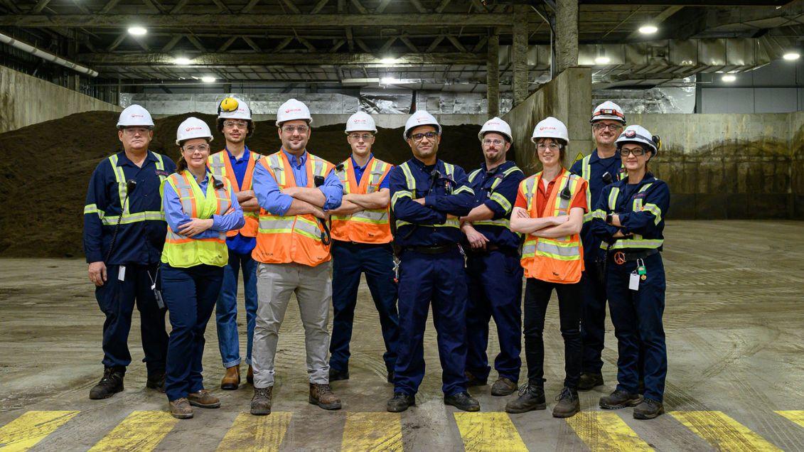 A group of Veolia employees stands in a facility smiling at the camera